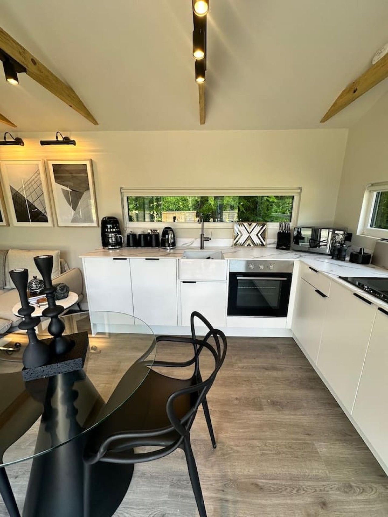 A modern kitchen with white cabinets, a dining table with chairs, and a window providing a view of greenery outside.