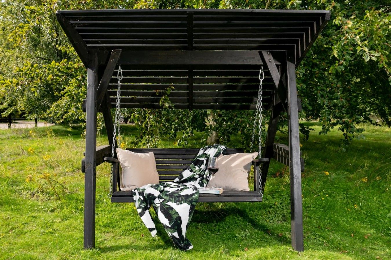 A wooden swing bed with cushions and a hanging plant.