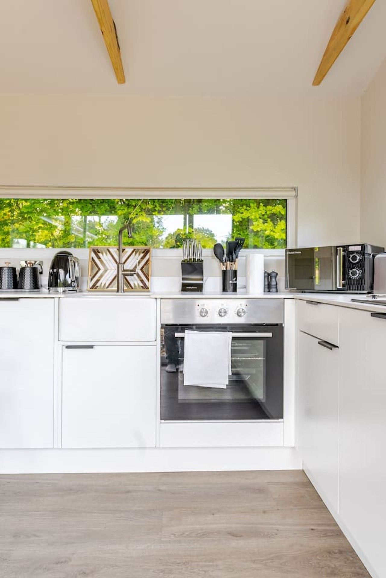 A modern kitchen with white cabinetry, a built-in oven, and a microwave.