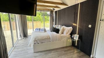 A bedroom with a bed, a TV mounted on the wall, and a view of the outdoors.