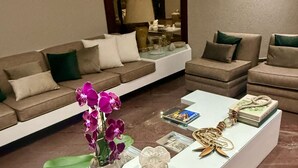 A modern living room with a white coffee table, two sofas, and a decorative vase with purple flowers. - Flat Golden Beach Pitangueiras with Sea View (Guarujá)