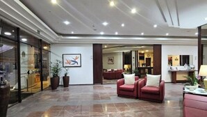 A spacious lobby with a marble floor, red sofas, and a reception desk. - Flat Golden Beach Pitangueiras with Sea View (Guarujá)