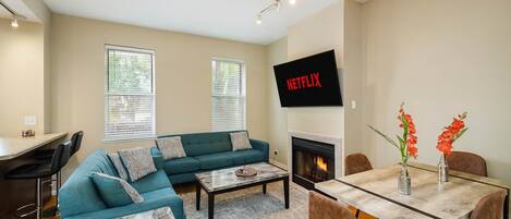 Una sala de estar con sofá, mesa de centro, chimenea, televisor y zona de comedor.