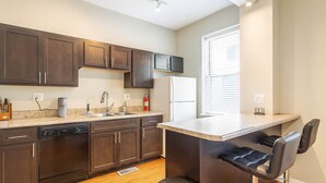 A modern kitchen with dark wood cabinets, a stainless steel sink, and a built-in bar area with bar stools. - Spacious 4BR Soulard Duplex - 2 Kitchens - Patio - Parking - Walk to Market (St. Louis)