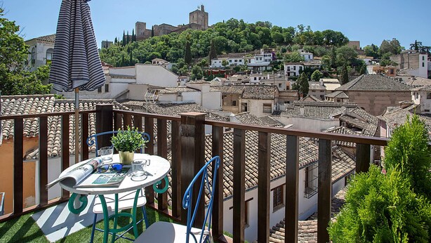 Una terrazza con tavolo, sedie e un ombrellone a righe.