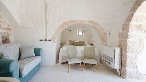 Quarto com cama, duas cadeiras, um sofá e um radiador.
