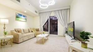 A modern living room with a sofa, coffee table, TV, and potted plants. - Silk Valley-Luxury 3B close to Beach (Abu Dhabi)