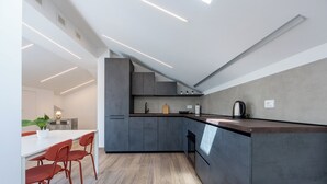 A modern kitchen with grey cabinets, a white countertop, and a dining area with red chairs. - Chieri - The den of dreams with panoramic terrace (Chieri)