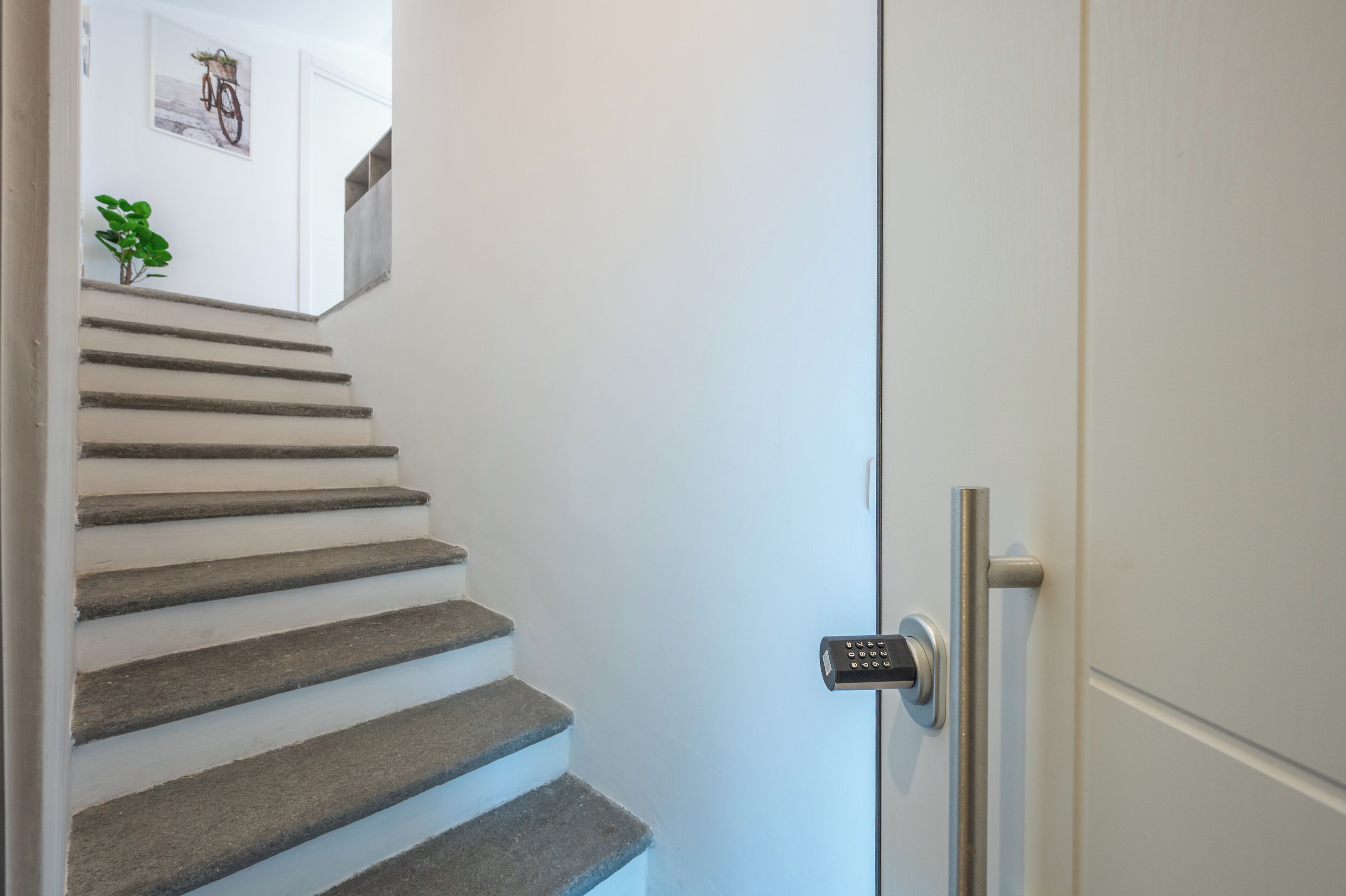 A staircase with a modern door and a security keypad.
