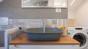 A modern bathroom with a large vessel sink, a mirror above, and a washing machine in the background. - Chieri - The den of dreams with panoramic terrace (Chieri)