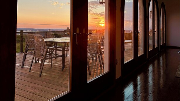 Una habitación con ventanas arqueadas amplias que dan a una terraza con mobiliario exterior.