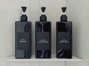 Tre sorte flasker med Artisan Stays produkter på en hvid reol.