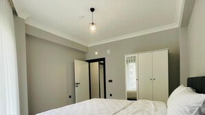 A modern bedroom with a large bed, a wardrobe, and a mirror.