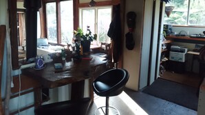 Une cuisine avec un plan de travail en bois, une chaise noire et une fenêtre donnant sur un paysage verdoyant.