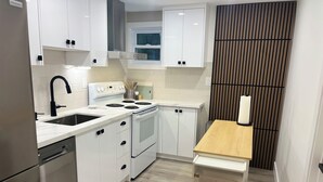 A modern kitchen with white cabinetry, a built-in oven, a sink, and a wooden countertop.