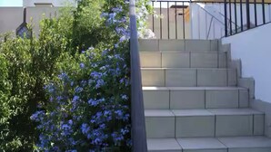 A set of beige steps leading up to a white wall with a black metal railing.
