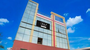 A modern building with a large glass facade, a prominent sign, and a red and yellow stripe. - Collection O Sector 4 Gurgaon (Gurugram)