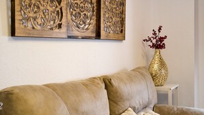 A beige sofa with a woven basket and a vase with red berries on a white side table.