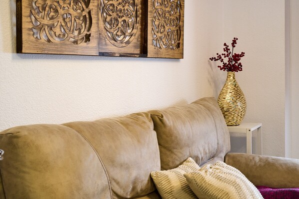 A beige sofa with a woven basket and a vase with red berries on a white side table.