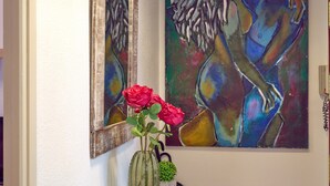 A painting, a vase with flowers, and a mirror on the wall.
