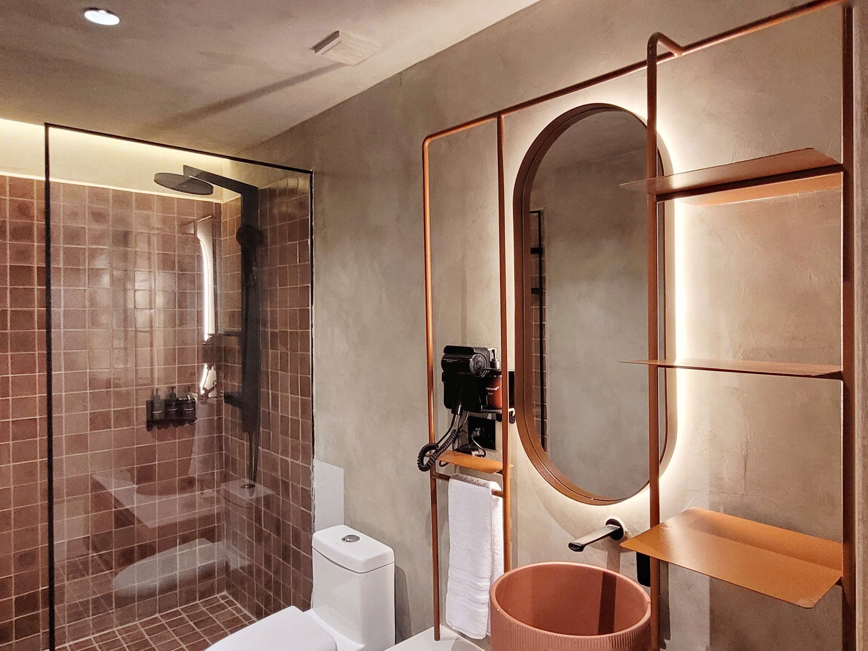 Une salle de bain moderne avec une douche à parois de verre, des toilettes, un lavabo avec un miroir et un porte-serviettes.