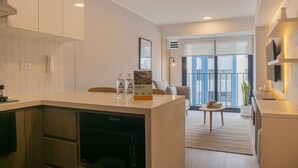 A modern kitchen with a built-in dishwasher, a dining area with a table and chairs, and a view of the city through large windows. - w Sunlit 1BR w Private Balcony in Miraflores (Lima)