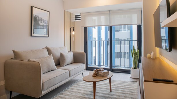 A modern living room with a sofa, a coffee table, and a TV. - w Sunlit 1BR w Private Balcony in Miraflores (Lima)