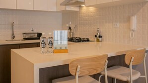 A modern kitchen with white cabinets, a central island with bar stools, a built-in stove, and a sink. - w Sunlit 1BR w Private Balcony in Miraflores (Lima)