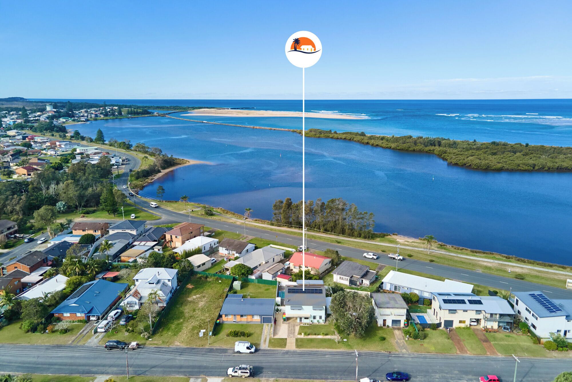 An aerial view of a residential area with houses, a road, and a large body of water.
