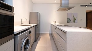 Eine moderne Küche mit Waschmaschine, Kühlschrank und Spüle.