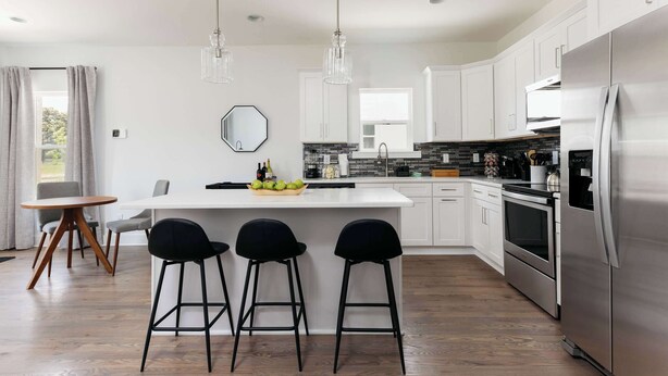 A modern kitchen with white cabinets, a stainless steel refrigerator, and a central island with bar stools. - Modern 4BR Retreat for 12, Near Downtown Nash! (Nashville)
