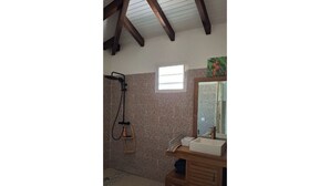 Un baño con ducha, lavamanos y ventana.