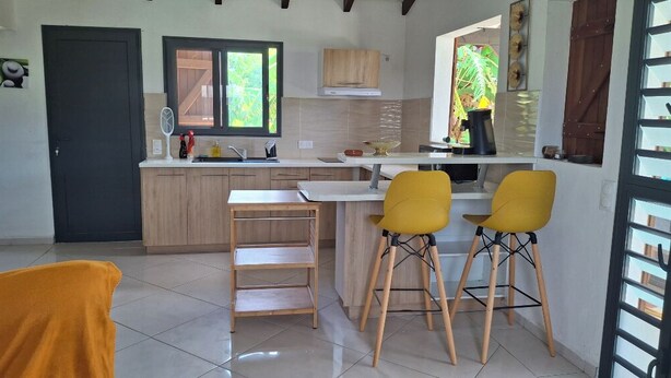 Una cocina con armarios de madera, encimera blanca y dos taburetes amarillos.