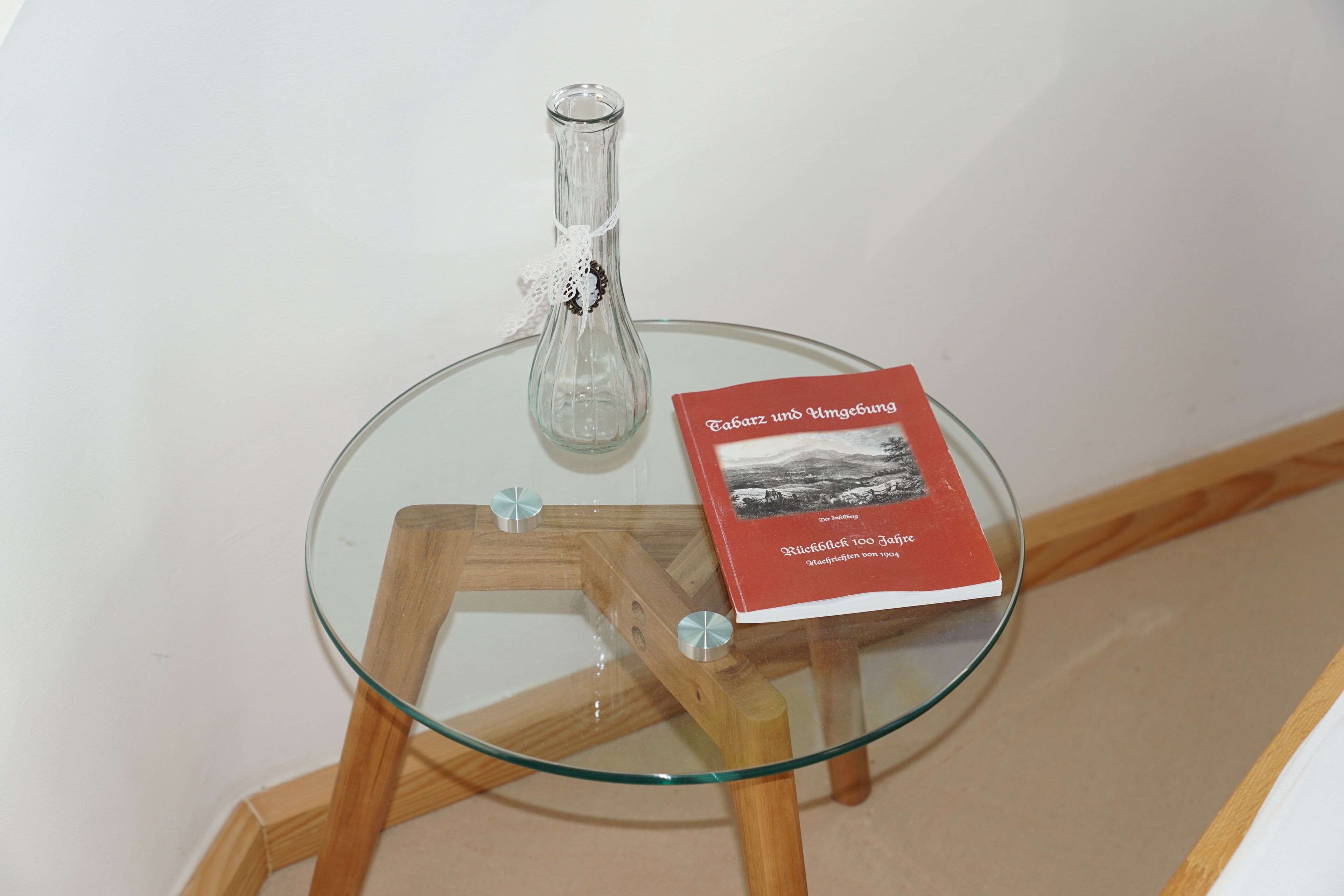 Une table en verre sur laquelle repose un livre intitulé « Tabarz ins Umgeburg » et une bouteille en verre transparent.