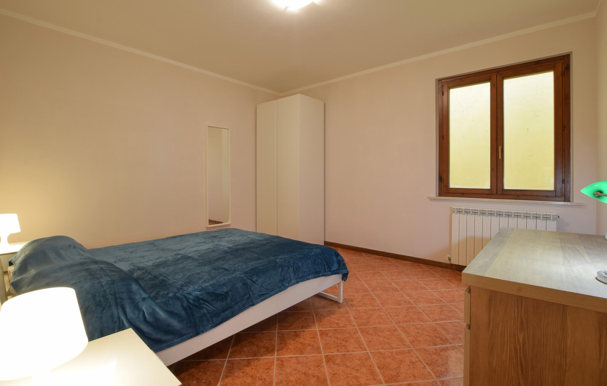 A bedroom with a bed, a dresser, a window, and a radiator.