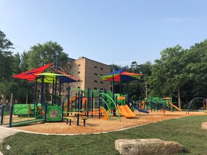 A playground with various play structures and a building in the background.