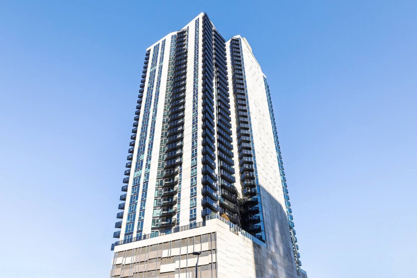 A tall, modern high-rise building with a prominent central core and multiple balconies.
