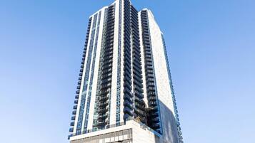 A tall, modern high-rise building with a prominent central core and multiple balconies.
