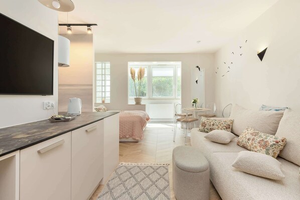 A modern living room with a sofa, a TV, and a dining area with chairs.