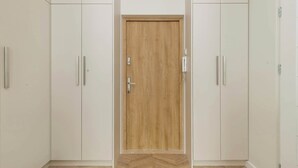 Una habitación con puerta de madera, armarios blancos y suelo con patrón de espiga.