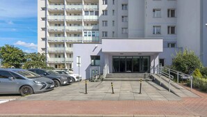 Un edificio residencial de varios pisos con estacionamiento y entrada porticada.