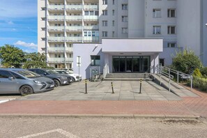 A multi-story residential building with a parking area and a gated entrance.
