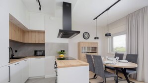 Une cuisine moderne avec des armoires blanches, un plan de travail en bois et un four à micro-ondes encastré.