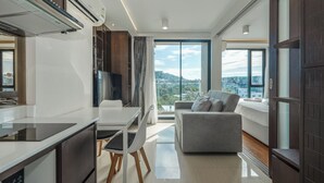 A modern living room with a sofa, a dining table, and a kitchen area with a stove and cabinets. - TheAristoLuxury Beach Resort Phuket C153 (Choeng Thale)