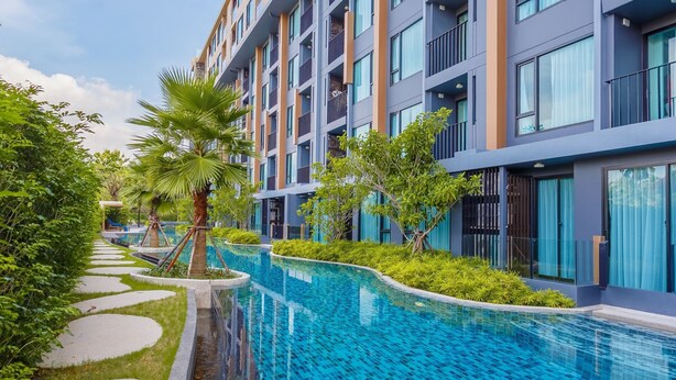 A modern hotel with a swimming pool, surrounded by greenery and a clear sky. - TheAristoLuxury Beach Resort Phuket C153 (Choeng Thale)
