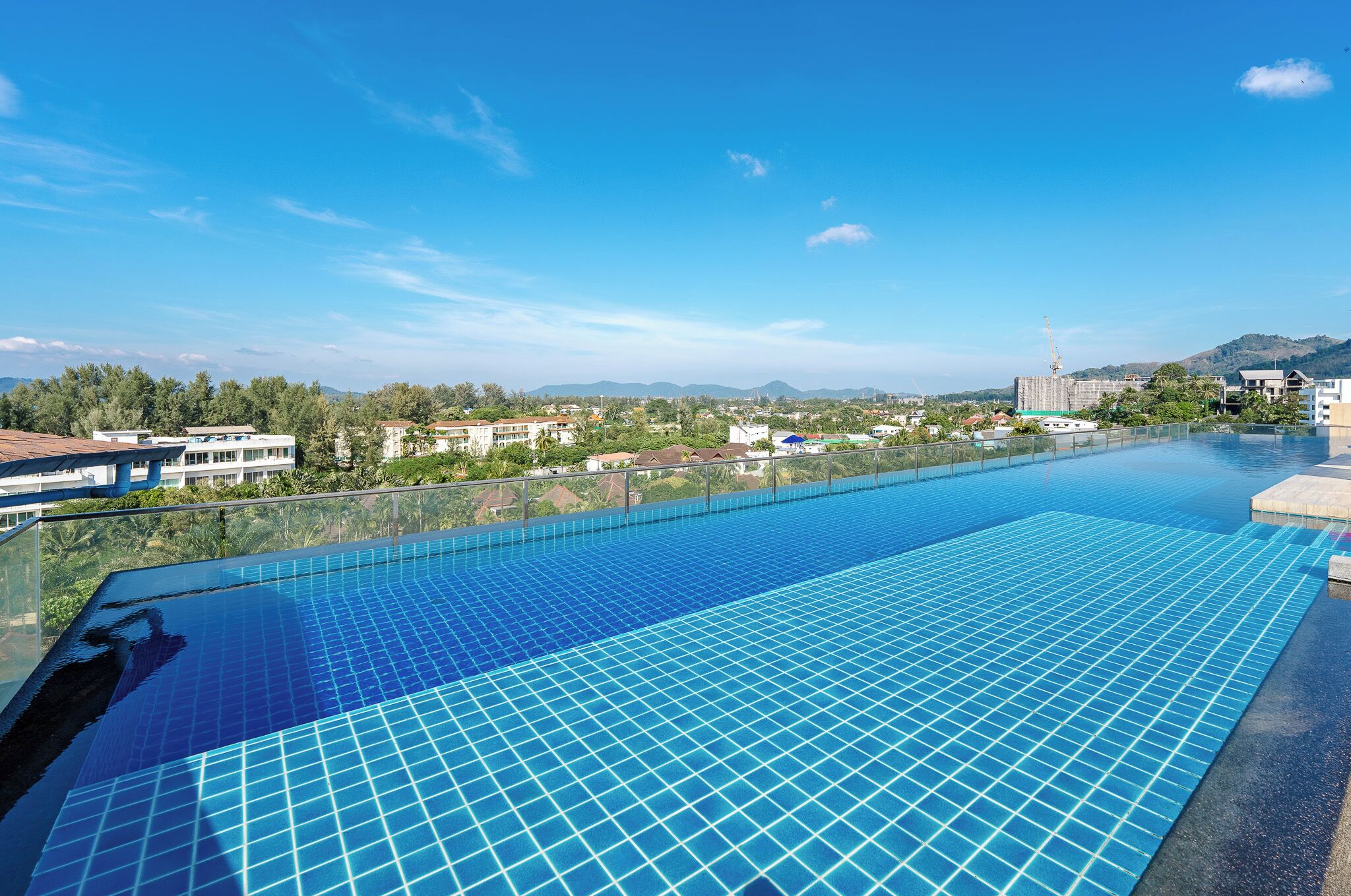 A large outdoor infinity pool with a clear view of the surrounding landscape, including buildings and mountains.