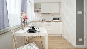 Une cuisine moderne avec des meubles blancs, un four à micro-ondes et un coin repas comprenant une table et des chaises.