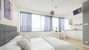 Une chambre moderne équipée d’un lit, d’un bureau et d’une kitchenette.