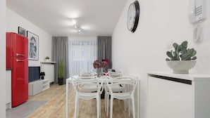 Una cocina moderna con armarios blancos, un refrigerador rojo y una mesa de comedor con sillas blancas.