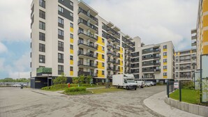 Un edificio residencial de varios pisos con balcones, una zona de estacionamiento y una entrada portonada.
